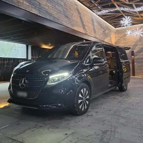 Black Mercedes van with open side door under an awning