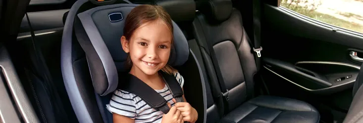 Child secured in a car seat in the back of a vehicle
