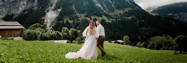 A married couple in a meadow at the foot of the mountains